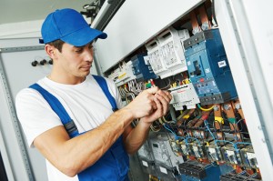 Young adult electrician builder engineer screwing equipment in f